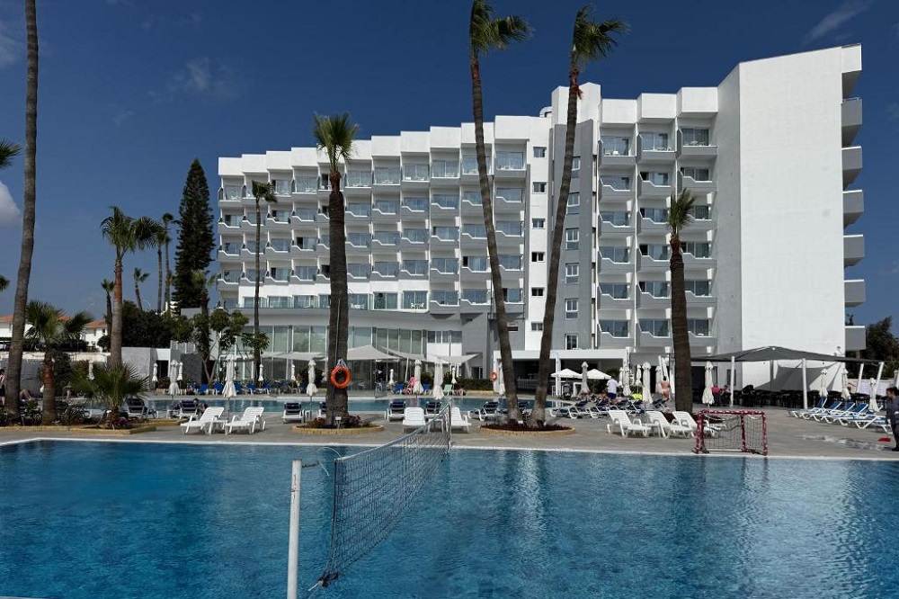 A Papouis hotel pool framed by palms under a Cyprus sky